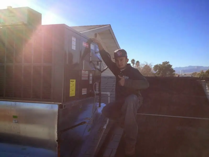HVAC technician performing AC Tune-Up on a rooftop unit in Albion
